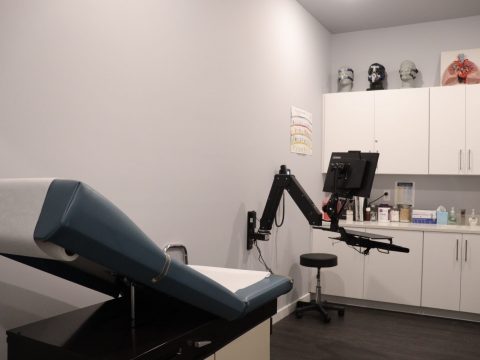 patient exam room with white cabinets and medical testing equipment